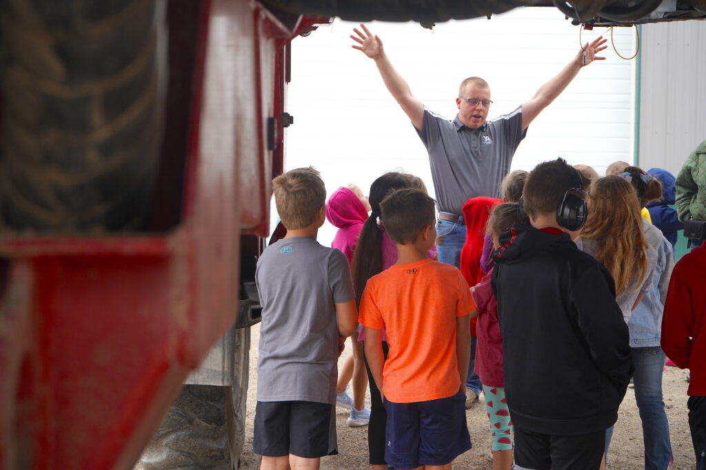 Youngblut Ag’s Garrett Princehouse, center back, explains how to stay safe around a crop sprayer to DG Elementary students in Sherry Parker’s second-grade class